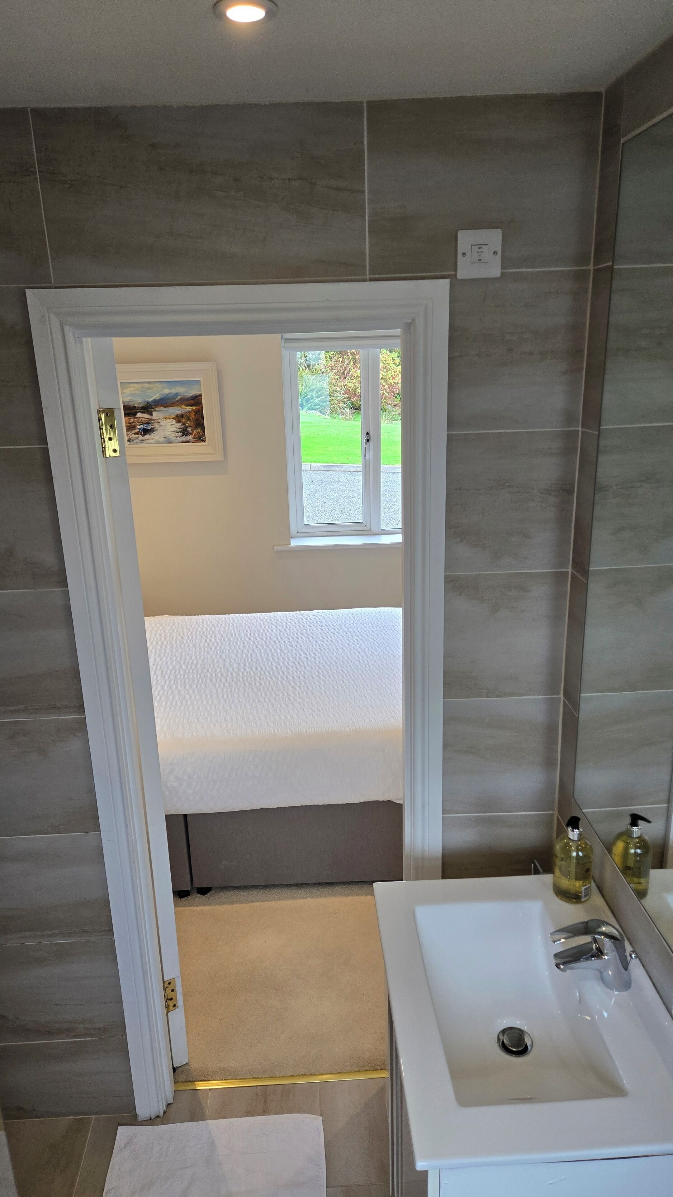 A bathroom with a white sink, a mirror, and a window.