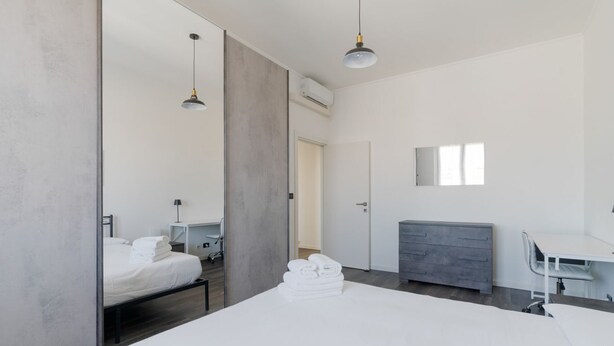 Une chambre d’hôtel moderne équipée d’un grand lit, d’un bureau, d’une chaise, d’une armoire et d’un miroir.