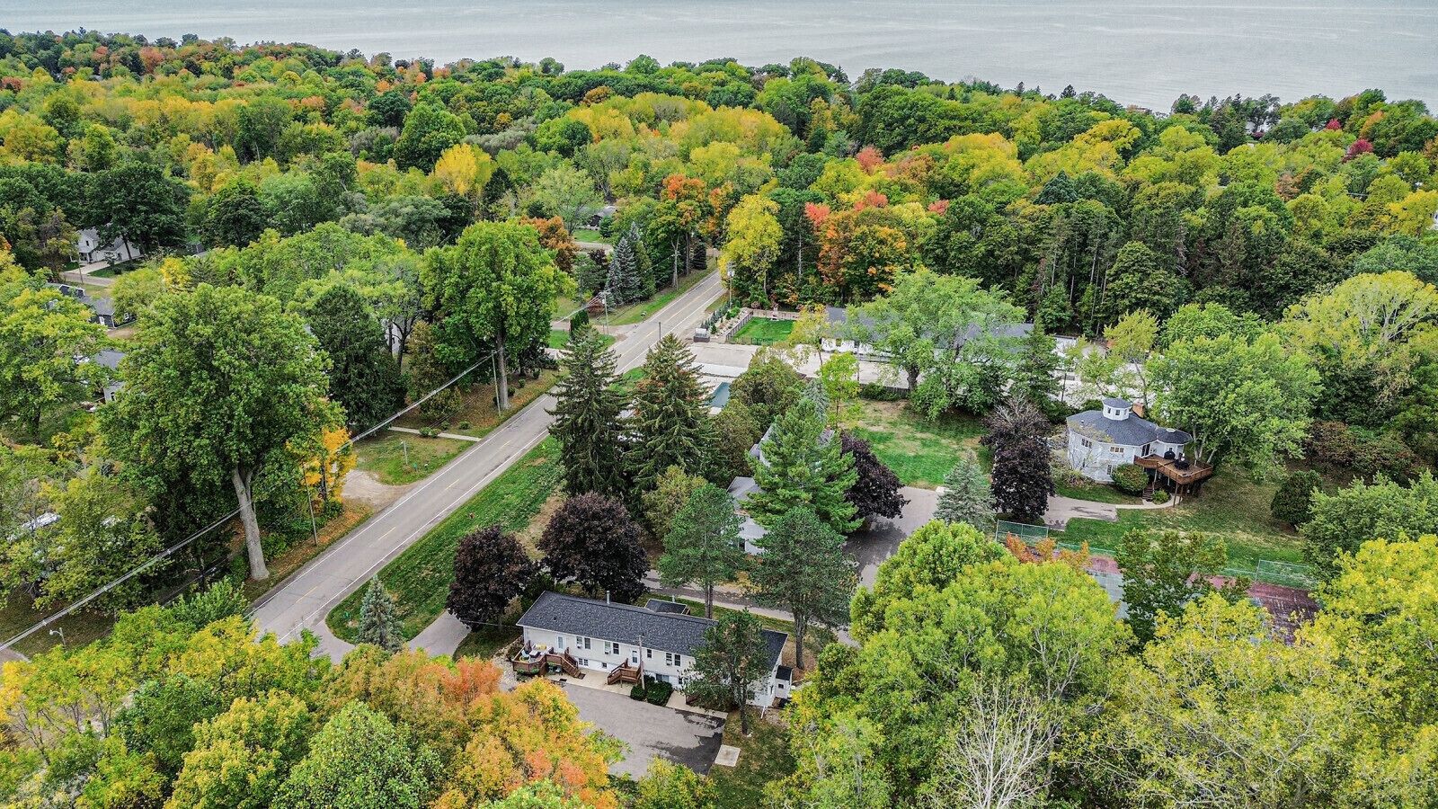 Vue aérienne d’un quartier résidentiel avec des maisons, des routes et une étendue d’eau en arrière-plan.