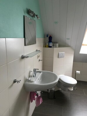 Ein Badezimmer mit Waschbecken, Spiegel, Toilette und Mülleimer.