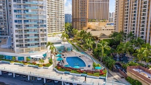 A high-rise hotel with multiple balconies, a swimming pool, and lush landscaping. - @ Marbella Lane Dreamy Sunset Views by the Sea (Honolulu)