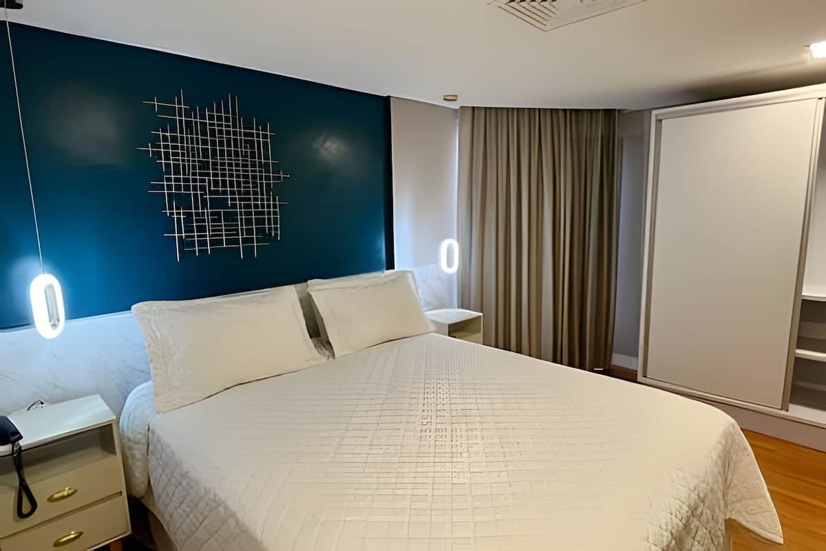 A bedroom with a bed, bedside tables, a wall-mounted light fixture, and a wardrobe.