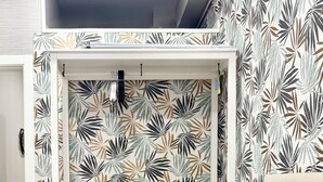 Ein Schlafzimmer mit einem Bett, Kissen, einer Bank und einer Wand mit einem Blattmuster.
