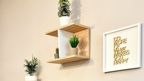 Ein Wohnzimmer mit Flachbildfernseher auf Holzständer, umgeben von Pflanzen und einem motivierenden Zitat.