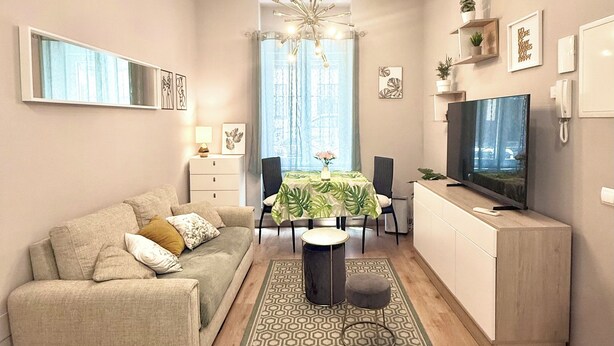 Ein modernes Wohnzimmer mit einer Couch, einem Esstisch und einem Fernseher.