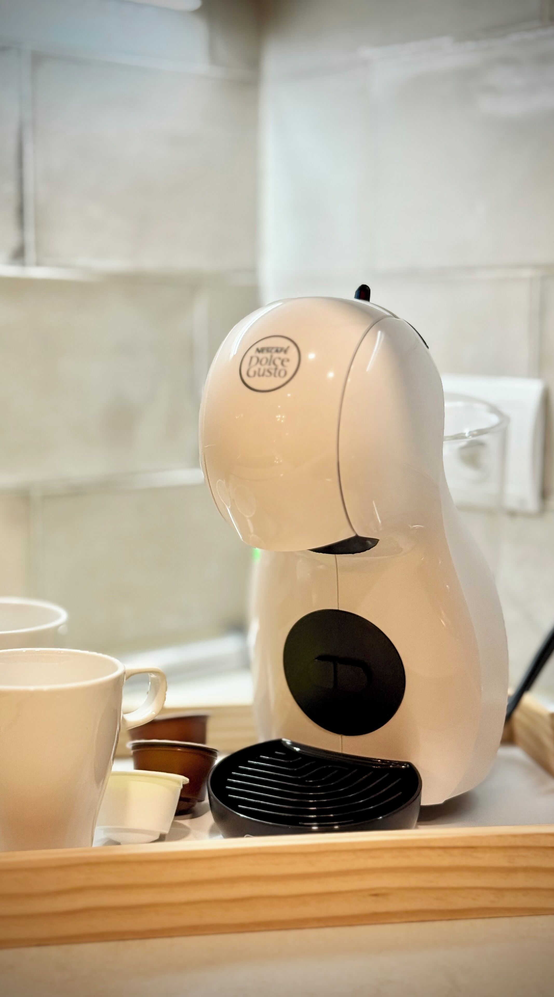 Een keukenhoek met een koffiezetapparaat, een dienblad met bekers en een waterkoker.