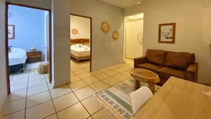 Een hotelkamer met een bed, een houten nachtkastje, een bruine bank, een kleine ronde tafel en een plafondventilator.