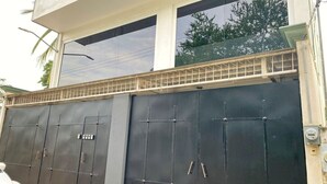 Een groot gebouw met poort en plat dak, voorzien van een balkon met metalen hekwerk.