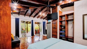 Quarto com cama, vigas de madeira no teto, televisão e guarda-roupa.