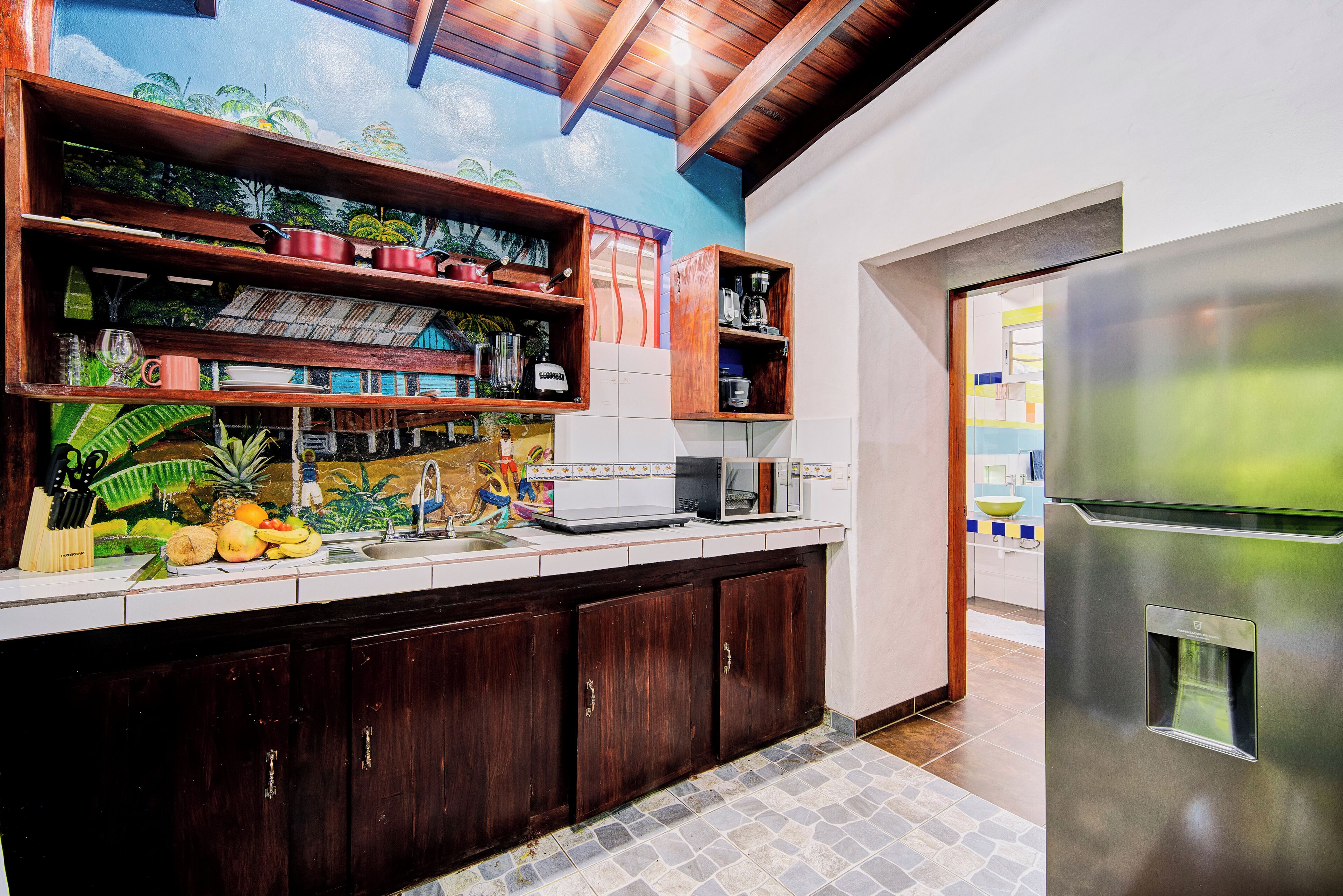 A kitchen with wooden cabinets, a stainless steel refrigerator, and a tiled backsplash.