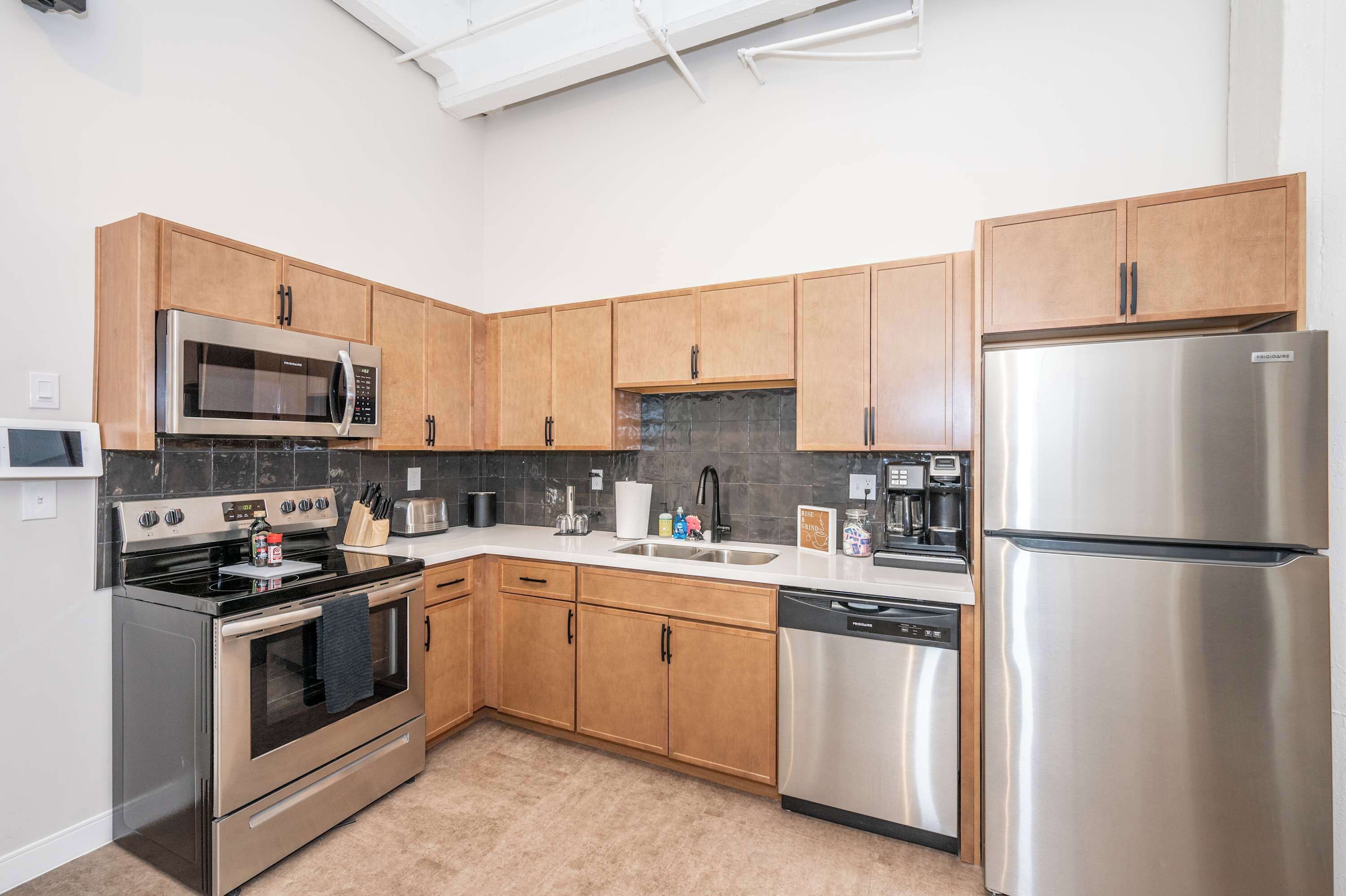 A modern kitchen with stainless steel appliances, wooden cabinets, and a dishwasher.