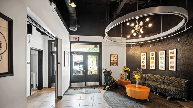 Eine moderne Lobby mit einer Rezeption, einer Couch, einem Couchtisch und gerahmten Bildern an der Wand.