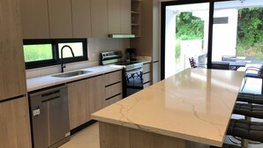 Una cocina moderna con una isla grande, electrodomésticos de acero inoxidable y vistas al exterior.