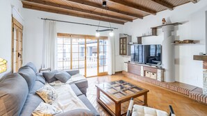 Un salon spacieux avec un plafond en bois, un grand canapé, une table basse et un téléviseur.