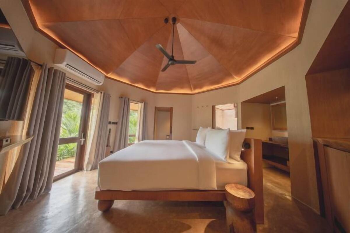 Un dormitorio amplio con una cama grande, un ventilador de techo y vistas a zonas verdes.