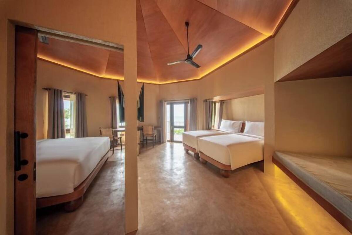 Una habitación de hotel con una cama grande, una cama más pequeña, un escritorio y una silla.