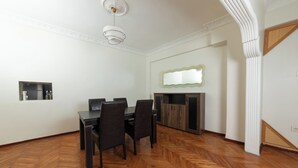 A dining area with a wooden herringbone floor, a dark wooden table, and four chairs. There is a white ceiling with a modern light fixture and a decorative mirror on the wall. - In the Center of Ancient Lands-2 (İstanbul)