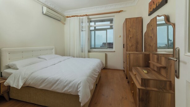 A bedroom with a bed, wooden wardrobe, and a window with a view. - In the Center of Ancient Lands-2 (İstanbul)