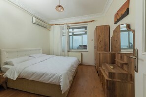 A bedroom with a bed, wooden wardrobe, and a window with a view. - In the Center of Ancient Lands-2 (İstanbul)