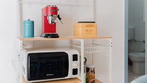 Eine kleine Küchenzeile mit Kaffeemaschine, Mikrowelle und Aufbewahrungsbox für Kaffee.