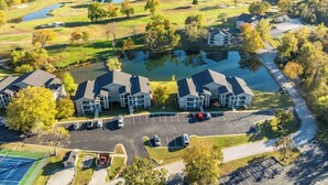 A golf course with a pond, surrounded by residential buildings with parking. - Peaceful 2BR Condo by Golf Course & Pools (Branson)