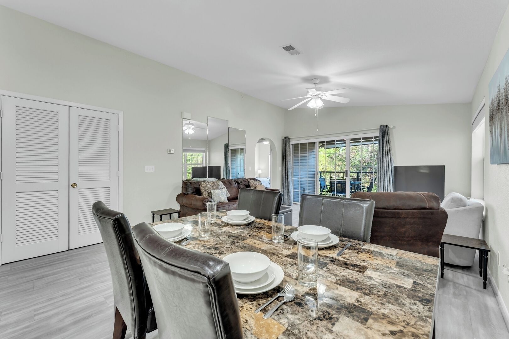 A dining area with a marble table, chairs, and a ceiling fan.