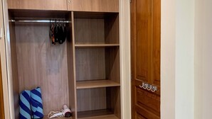 Un dressing avec des étagères en bois, une tringle à vêtements et un meuble à tiroirs intégré.