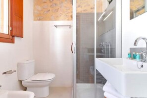 A bathroom with a toilet, a glass shower enclosure, and a sink with a mirror. - Mira Altea - A Luxurious Boutique Stay (Altea)