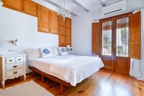 A bedroom with a wooden bed, white nightstands, a chandelier, and wooden doors. - Mira Altea - A Luxurious Boutique Stay (Altea)