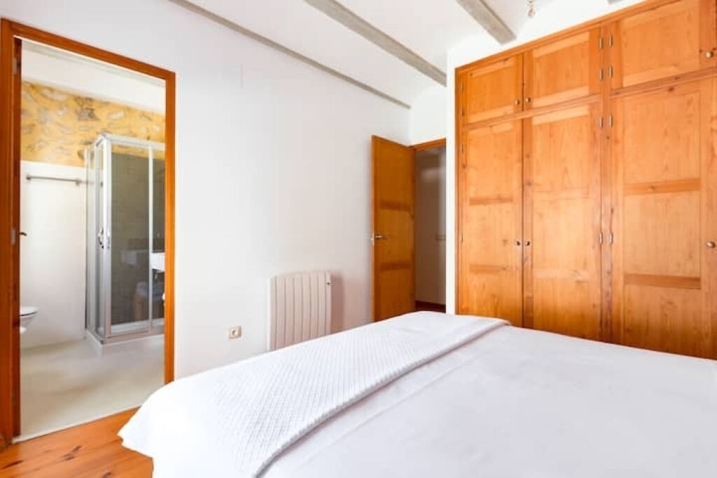 Quarto com cama grande, guarda-roupa de madeira e chuveiro.