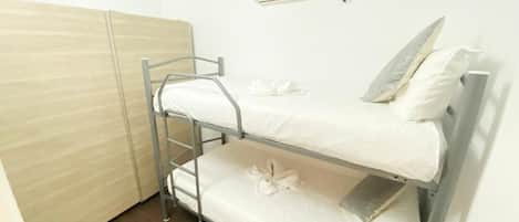 A bunk bed room with a wooden wardrobe, a white air conditioning unit, and a metal ladder.