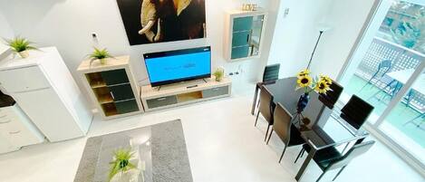 Un salon moderne doté d’un téléviseur à écran plat, d’un coin repas et d’une grande fenêtre donnant sur l’extérieur.