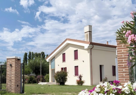 A two-story house with a brick chimney, a small garden with flowers, and a clear sky.. Mobile Home 'Casa Rosa 5' with Private Garden, Wi-Fi and Air Conditioning