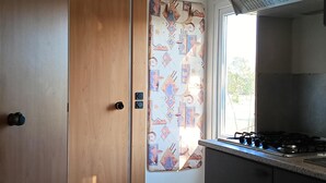 Cozinha compacta com fogão a gás, porta de madeira e cortina estampada.