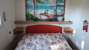 A bedroom with a bed, a headboard, a window, and a wall-mounted shelf. - Mobile Home 'Casa Gerbera 6' with Private Garden and Wi-Fi (Cavallino-Treporti)