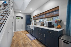 Een moderne keuken met een ingebouwde kookplaat, een koffieapparaat en een raam met zonwering.