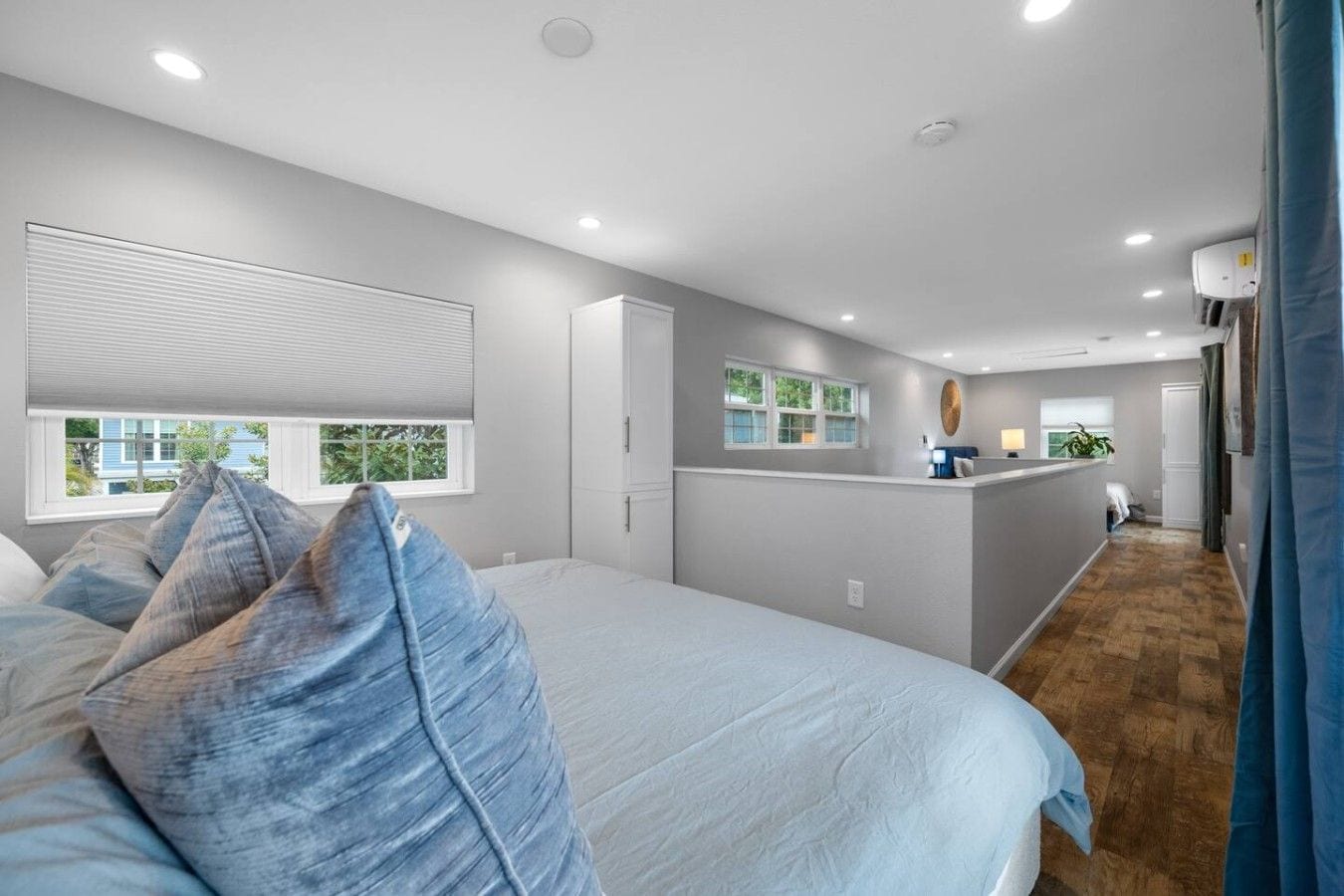 Un dormitorio con una cama grande, un escritorio y vistas al exterior por una ventana.