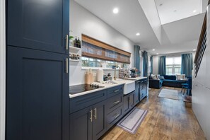 Une cuisine moderne avec des meubles de couleur sombre, un îlot central et un coin repas comprenant un canapé bleu et une table.