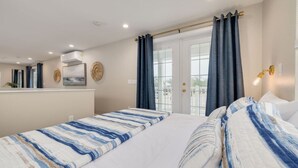 A hotel room with two beds, a large window with curtains, a ceiling fan, and a wall-mounted air conditioning unit. - Boutique Tiny House Escape with Pool | Sunny (Dunedin)