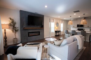 Ein modernes Wohnzimmer mit Kamin, einer Couch, einem Couchtisch und einem an der Wand befestigten Fernseher.