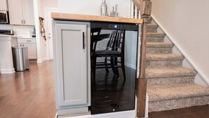 Eine kompakte Küche mit integriertem Geschirrspüler, einer Holz Arbeitsplatte und einer Treppe, die zu einer anderen Ebene führt.