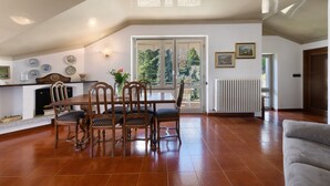 Een eethoek met een tafel, stoelen, een open haard en uitzicht door een raam.