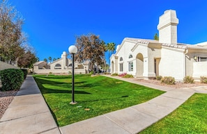 A residential area with a well-maintained lawn, a sidewalk, and a row of houses with a similar architectural style. - Stylish 2BR 2BA Chandler Townhome with Vaulted Ceilings & private patio (Chandler)