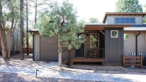 Eine moderne Holzhütte mit verdeckter Veranda und einem Schotterweg.