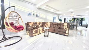 A modern living room with a sectional sofa, a hanging chair, and a small round table. - NEW Luxury 4BR Family Villa | Private Pool & Spa | Gated Community (Bon Accord, Tobago, Trinidad and Tobago)