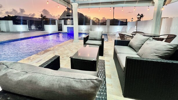 An outdoor pool area with seating and a covered patio. - NEW Luxury 4BR Family Villa | Private Pool & Spa | Gated Community (Bon Accord, Tobago, Trinidad and Tobago)