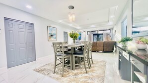 A modern dining area with a marble floor, a dining table with chairs, a sofa, and a coffee table with plants. - NEW Luxury 4BR Family Villa | Private Pool & Spa | Gated Community (Bon Accord, Tobago, Trinidad and Tobago)