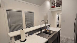 Een moderne keuken met een inbouwvaatwasser, een spoelbak en een raam met zonwering.