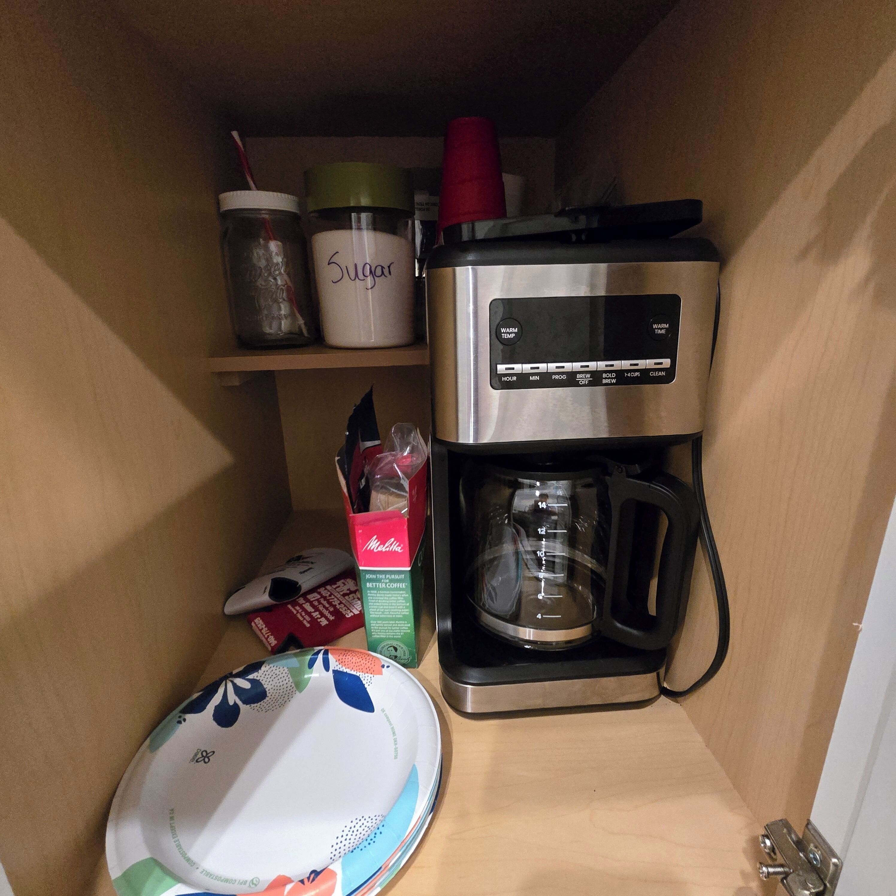 A kitchen with a coffee maker, sugar container, and a Melitta coffee box.