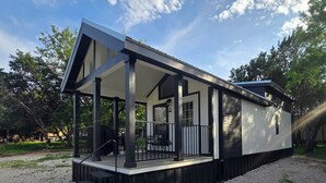 Een modern huis met een overdekte veranda, een trap en een grindpad.